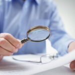 Forensic Document Examiner Studying With Magnifying Glass