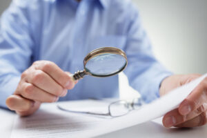 Forensic Document Examiner Studying With Magnifying Glass